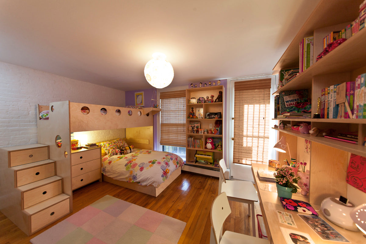 Spacious child's bedroom with a bunk bed, desk area, floral rug, and well-stocked bookshelves