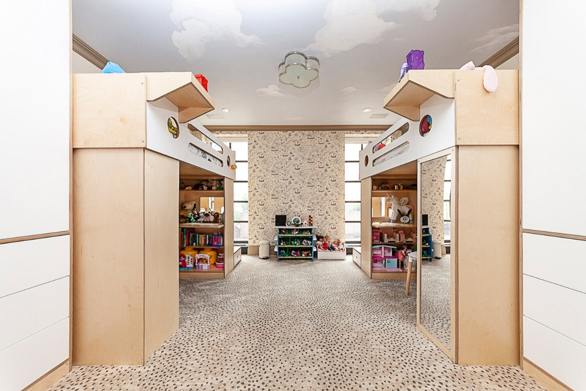 Playroom with wooden houses, shelves of toys, and cloud lamp.