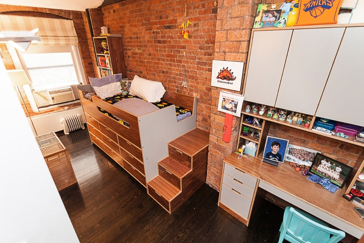 Cozy bedroom with loft bed, desk, shelves, and brick wall.