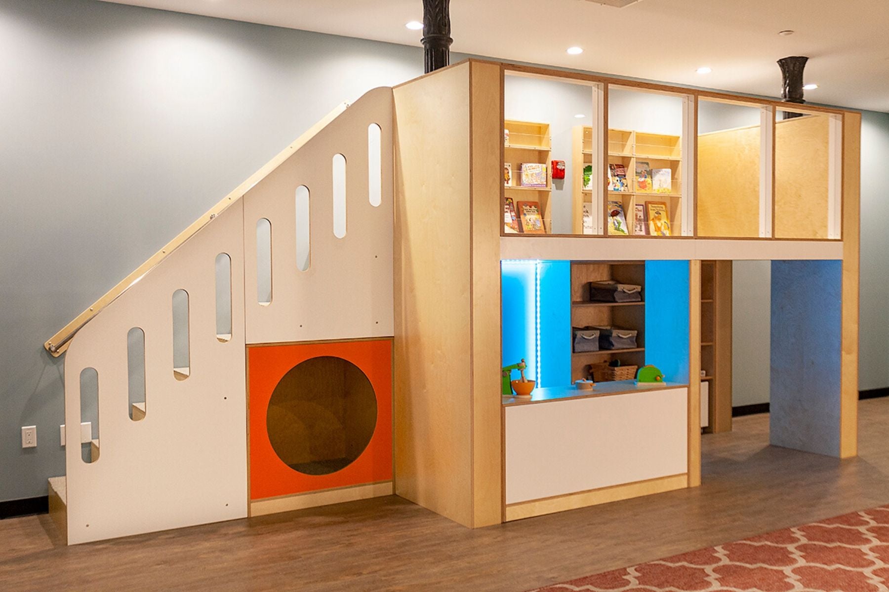 Colorful indoor wooden playhouse with stairs and storage.