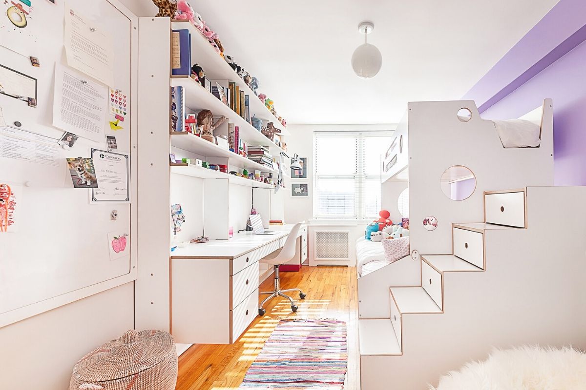 Bright room with white furniture, colorful rug, and shelves with toys