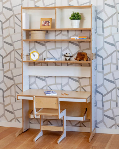 Stylish study nook with wooden desk and shelving against a geometric patterned wall.