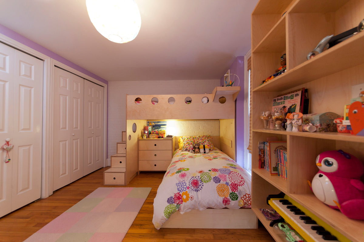 Colorful child's bedroom with floral bedding, wooden furniture, and a bright overhead light