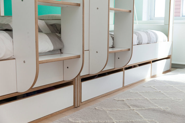 Modern bunk beds with circular windows and wooden frames, shown in a bright room with a white rug.