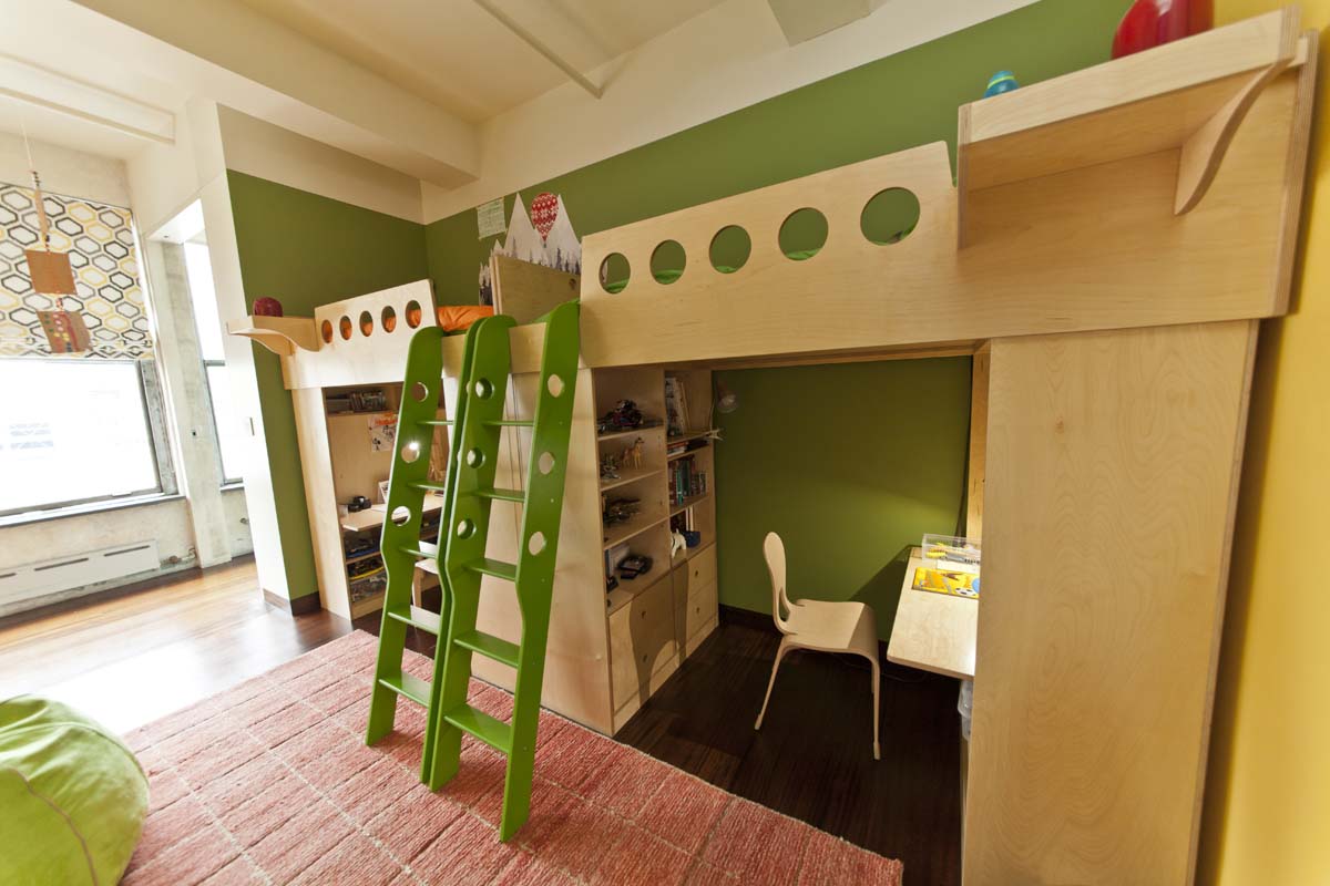 Green loft bed with ladder, desk, chair, and shelves in a child’s colorful room.
