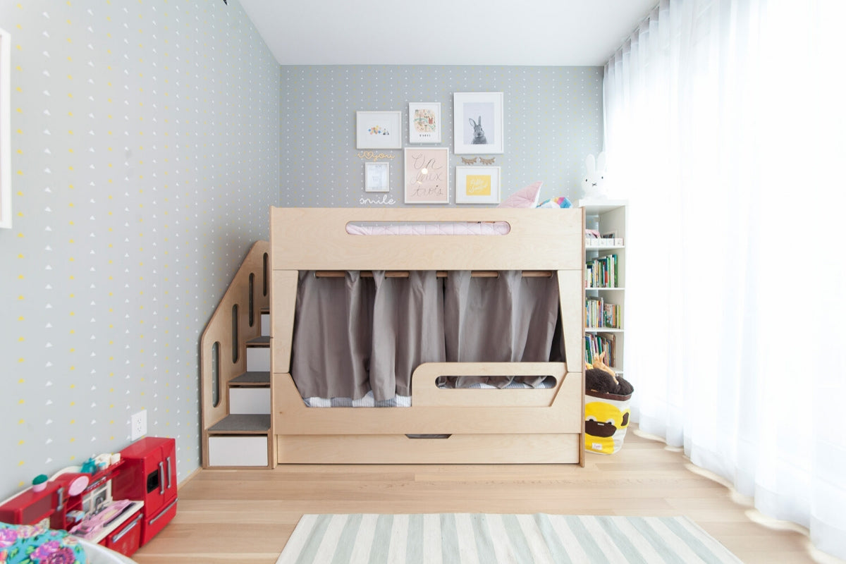 Child’s room with loft bed, bookshelf, toys, and polka dot wallpaper.