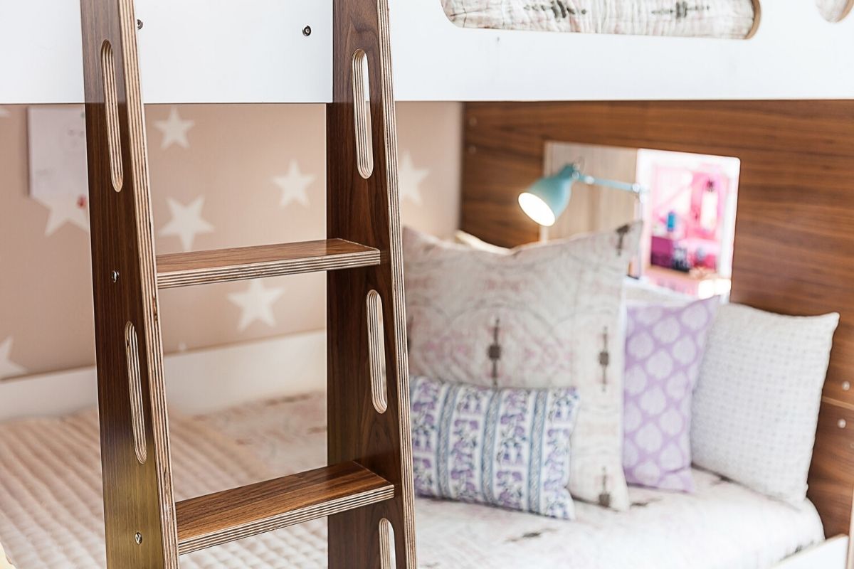 Cozy bunk bed with bedding and pillows on wooden ladder.
