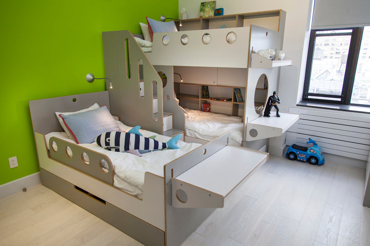 Bunk bed with stairs, lower bed extended, green and white decor, toys on floor.