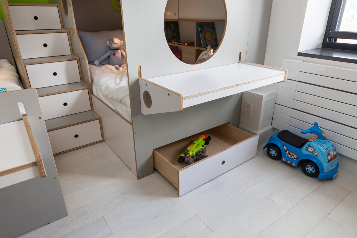 Child’s bedroom with bed, storage stairs, toy car, and toys in an open drawer.
