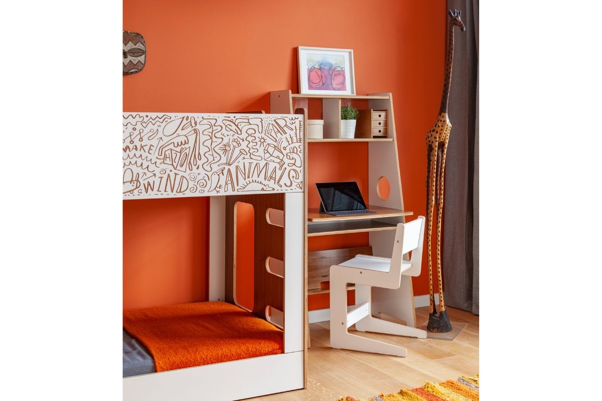 Modern bunk bed with desk, laptop, and wall art.