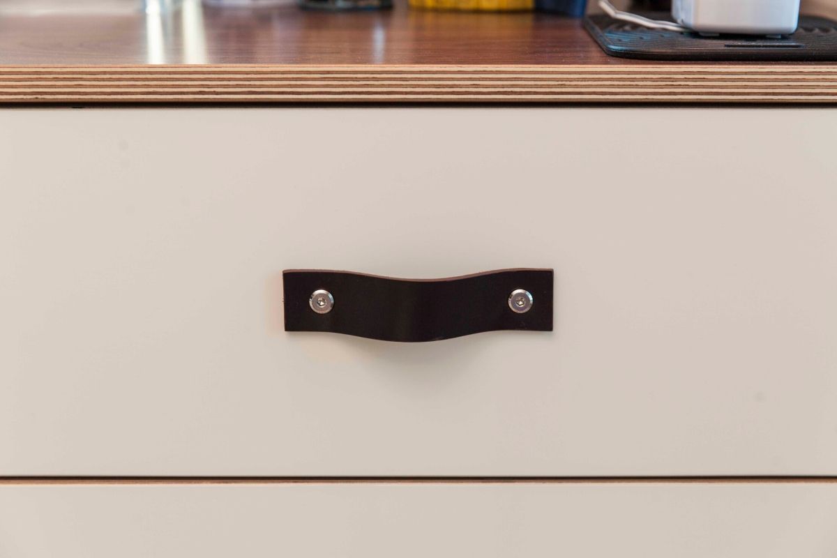 Close-up of a white drawer with a black handle on a wooden surface.