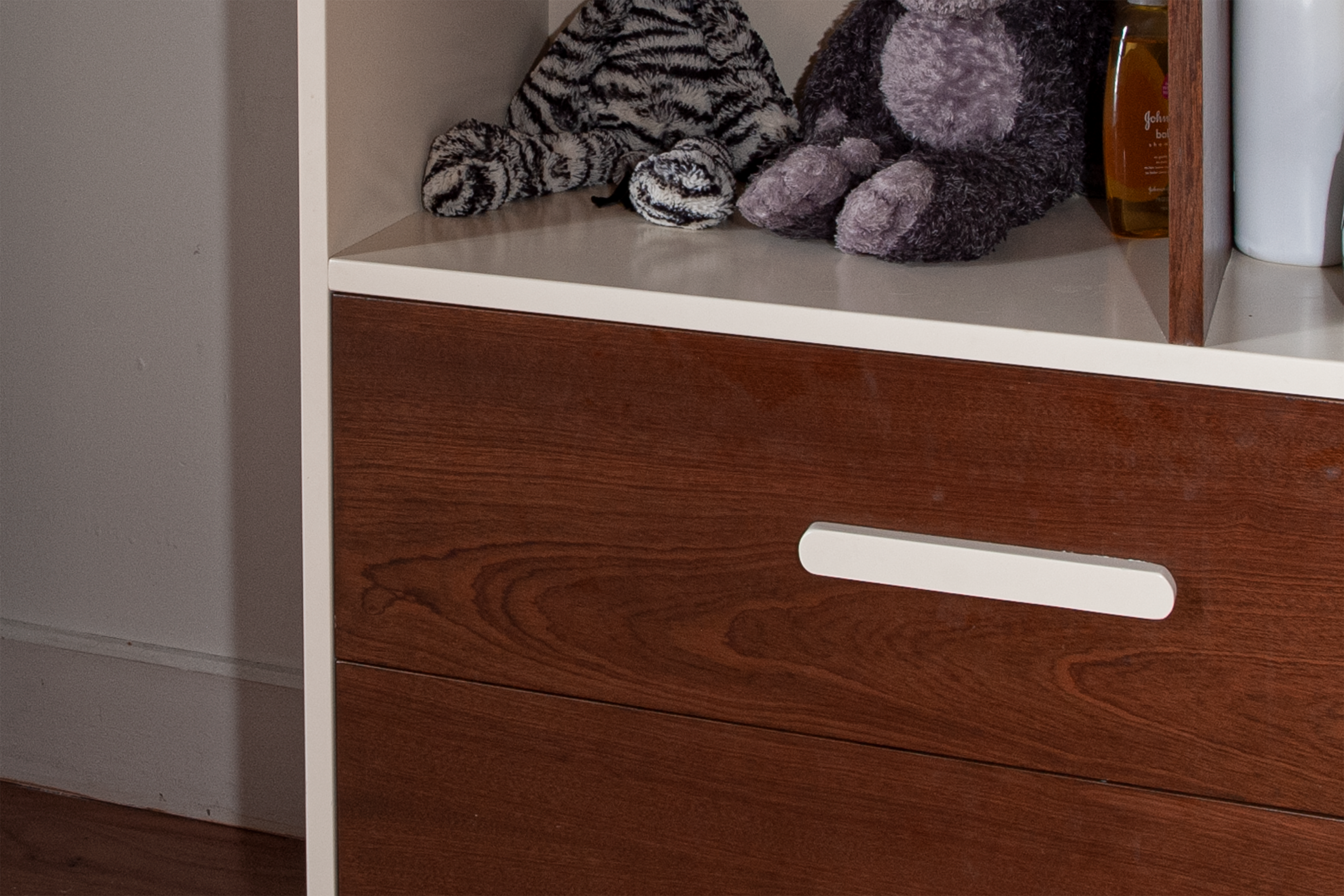 A wooden cabinet with a stuffed animal peeking out from an open drawer.