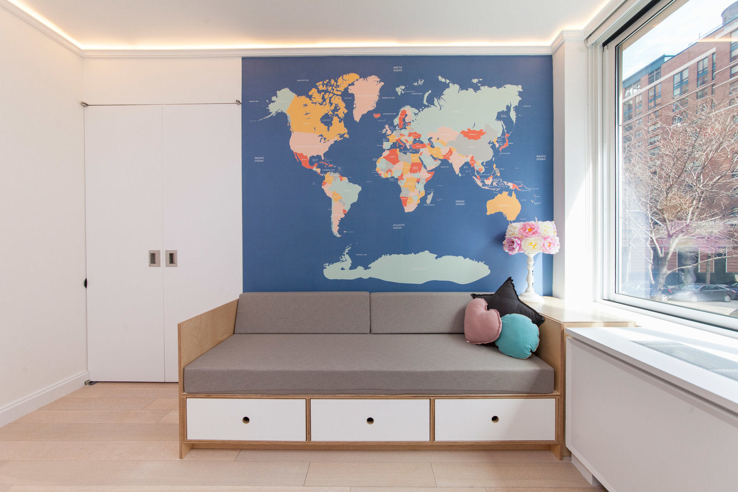 Modern room with a world map wall decor, sofa bed, and window view.