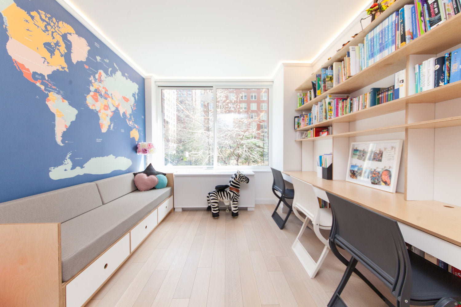 Bright room with map wall, bookshelves, desk, chairs, and window view.