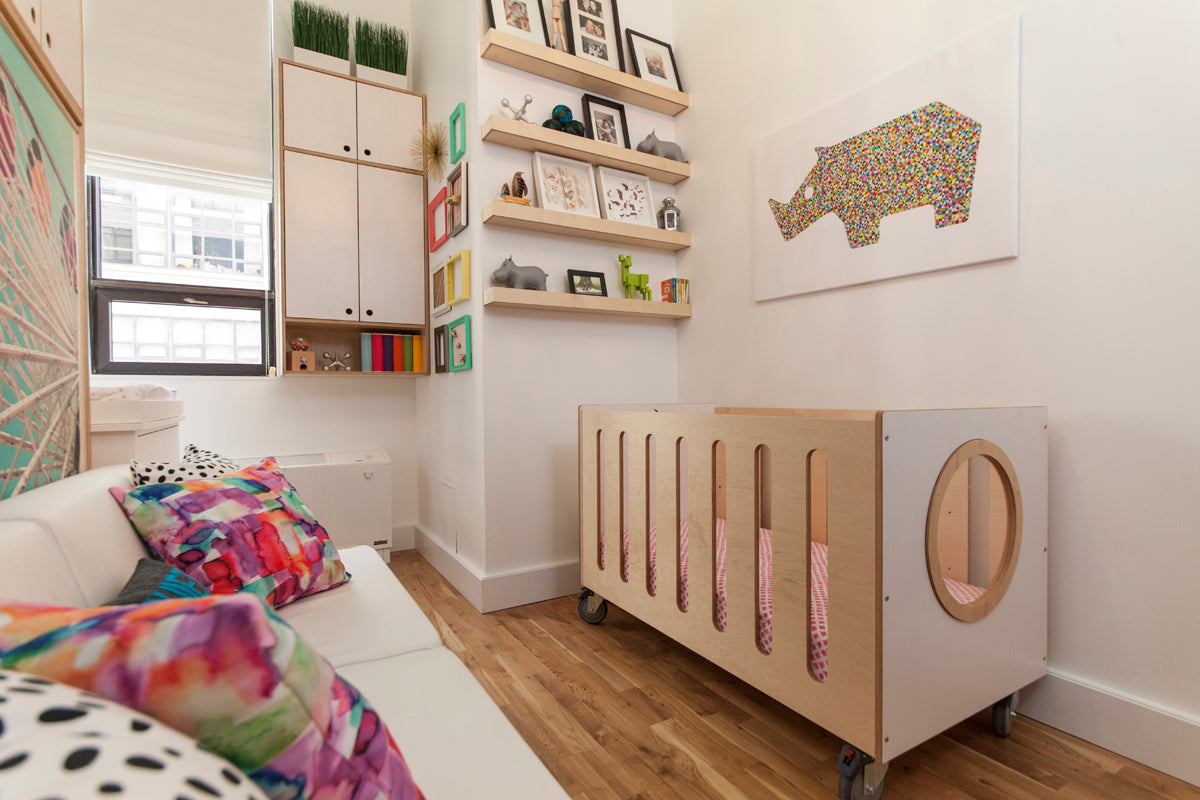 Cozy bedroom, colorful bedspread, wooden crib, shelving unit.