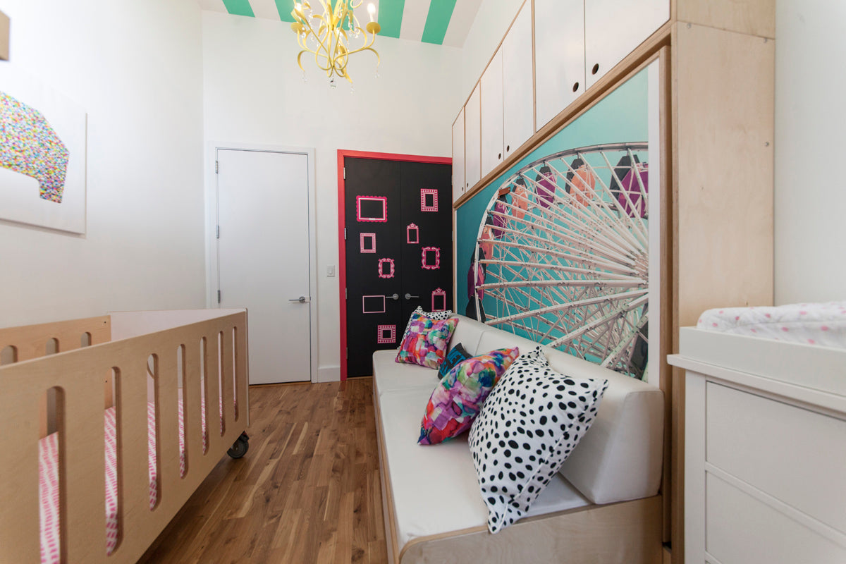 Chic nursery with crib, playful pillows, and vibrant wall art.