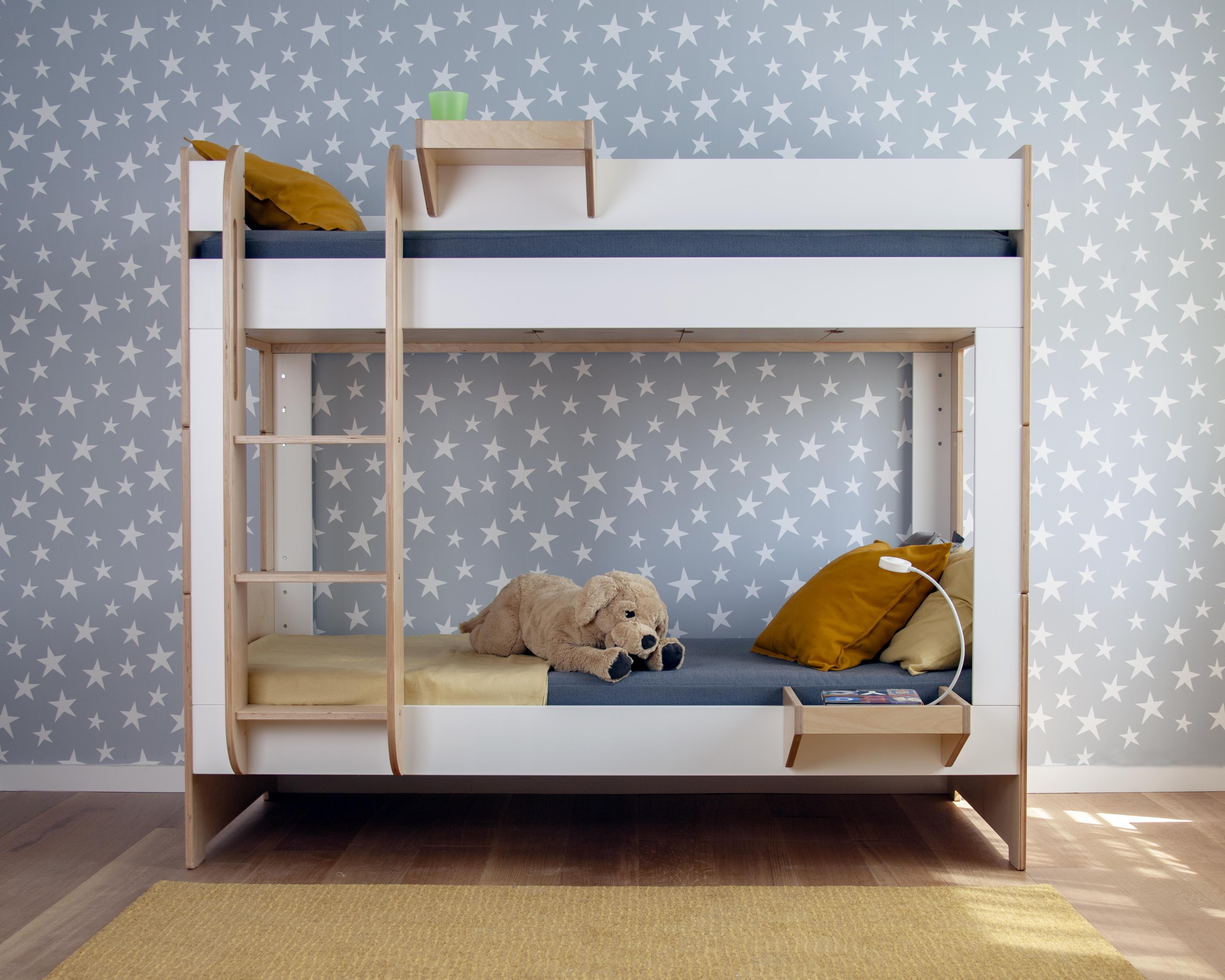 Modern bunk bed with stuffed animal on lower level, set against a light blue polka-dot wallpaper.