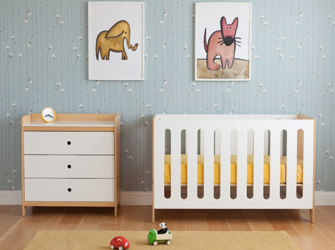 Baby's room with crib, dresser, toys, and two animal paintings on a blue wall.