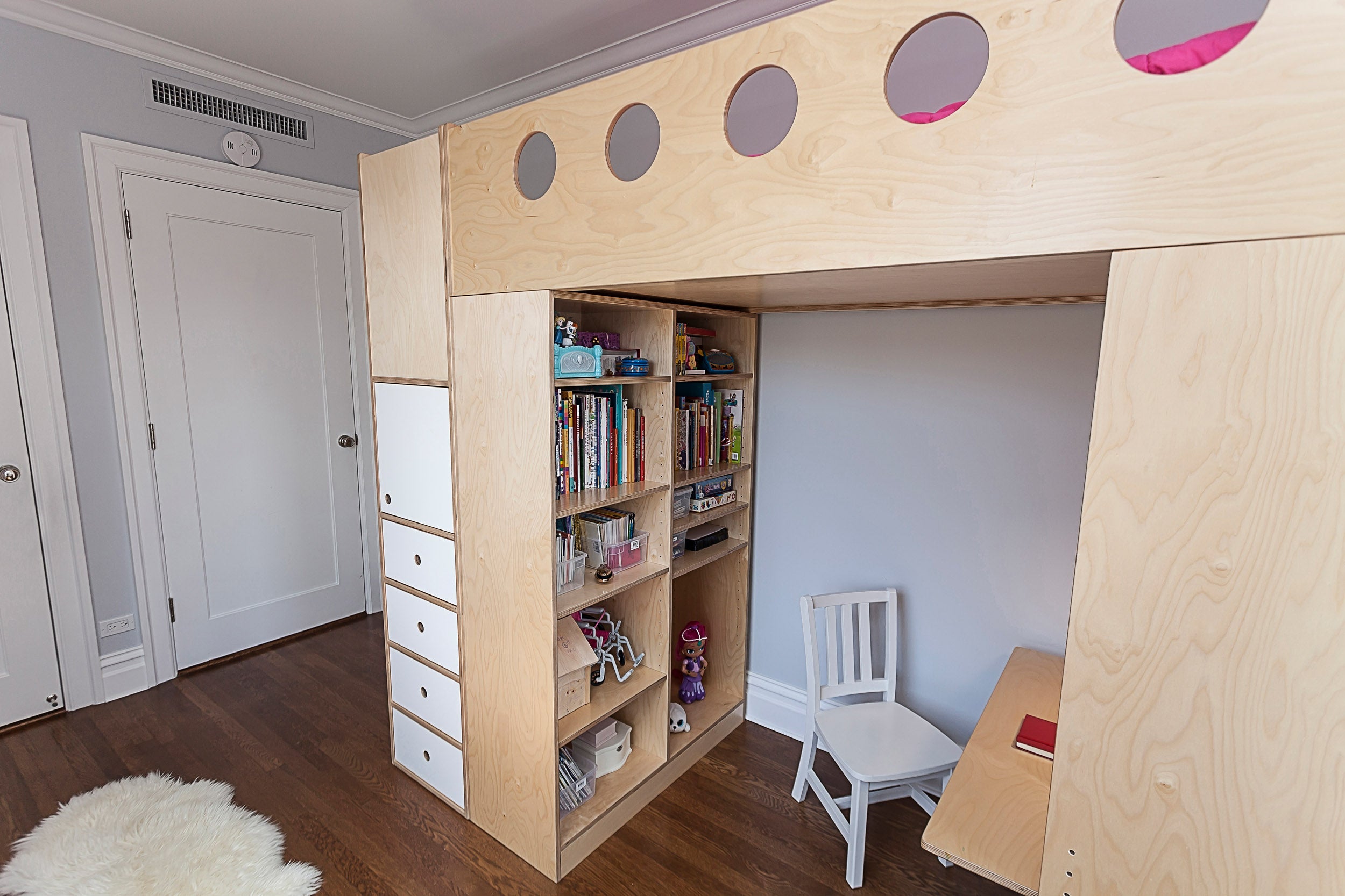 Loft bed with storage, small chair in a cozy room.