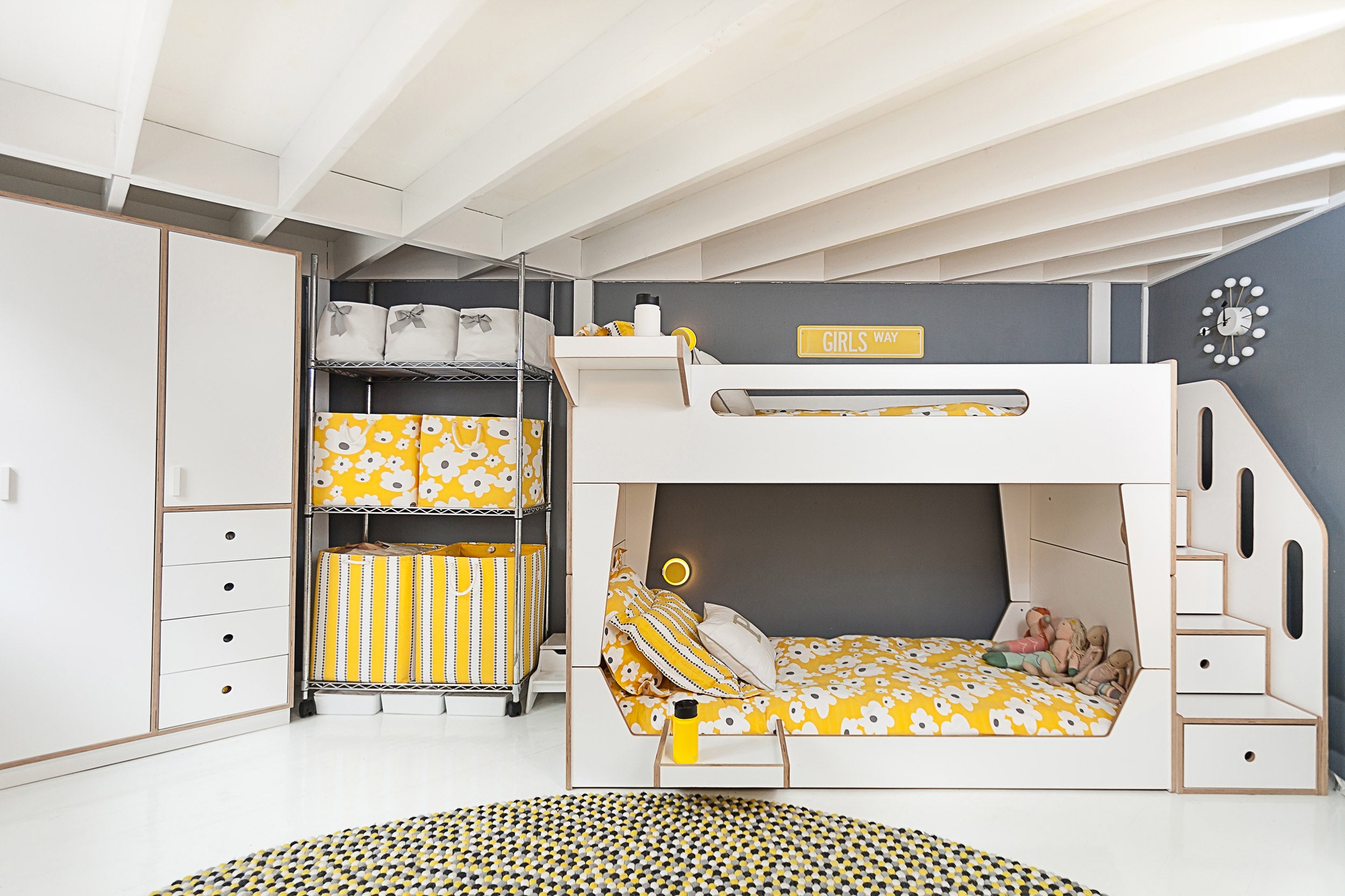 Kids’ room with bunk bed, yellow accents, storage, polka dot rug.