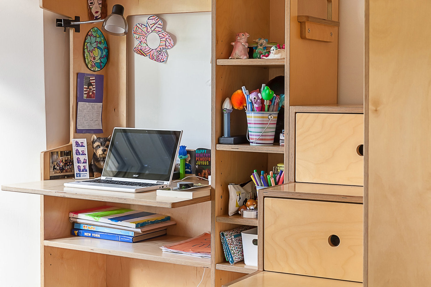 Wooden desk with laptop, books, and colorful stationery in a personal study space.