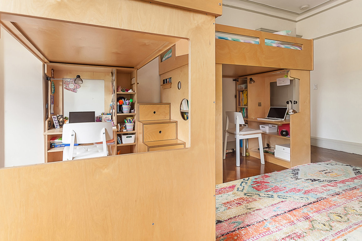 Compact loft bed with desk, storage, rug in room.