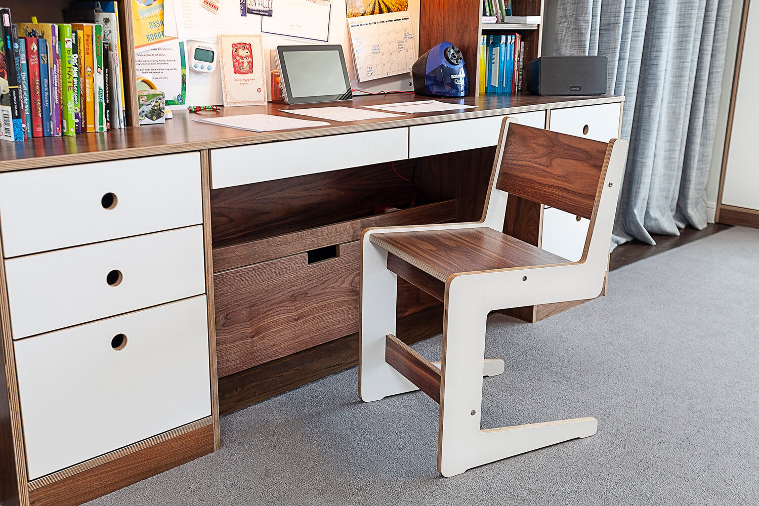 A desk with a laptop and chair on a carpet.