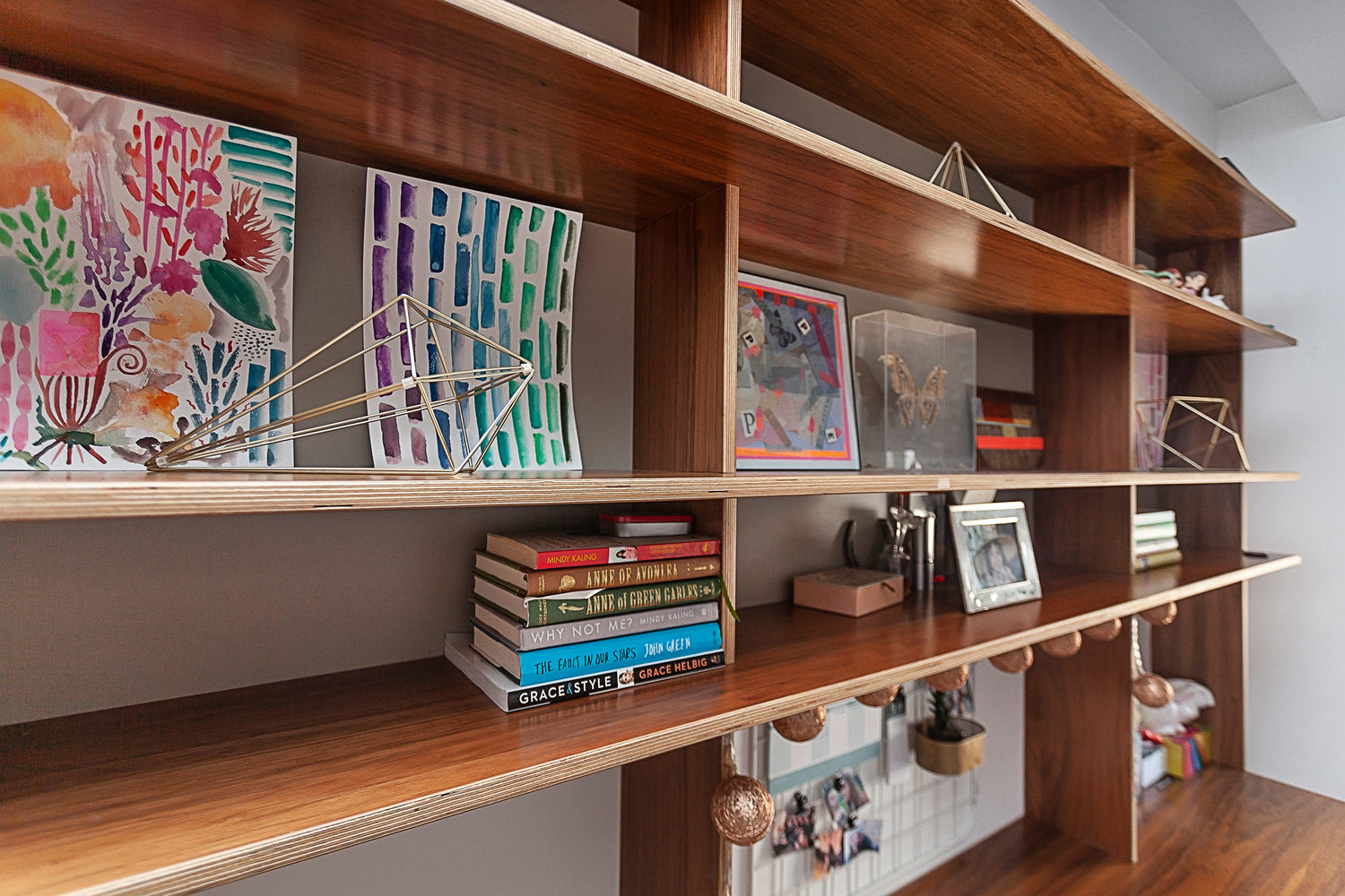 Assorted books, artwork, and decor on wooden shelves.
