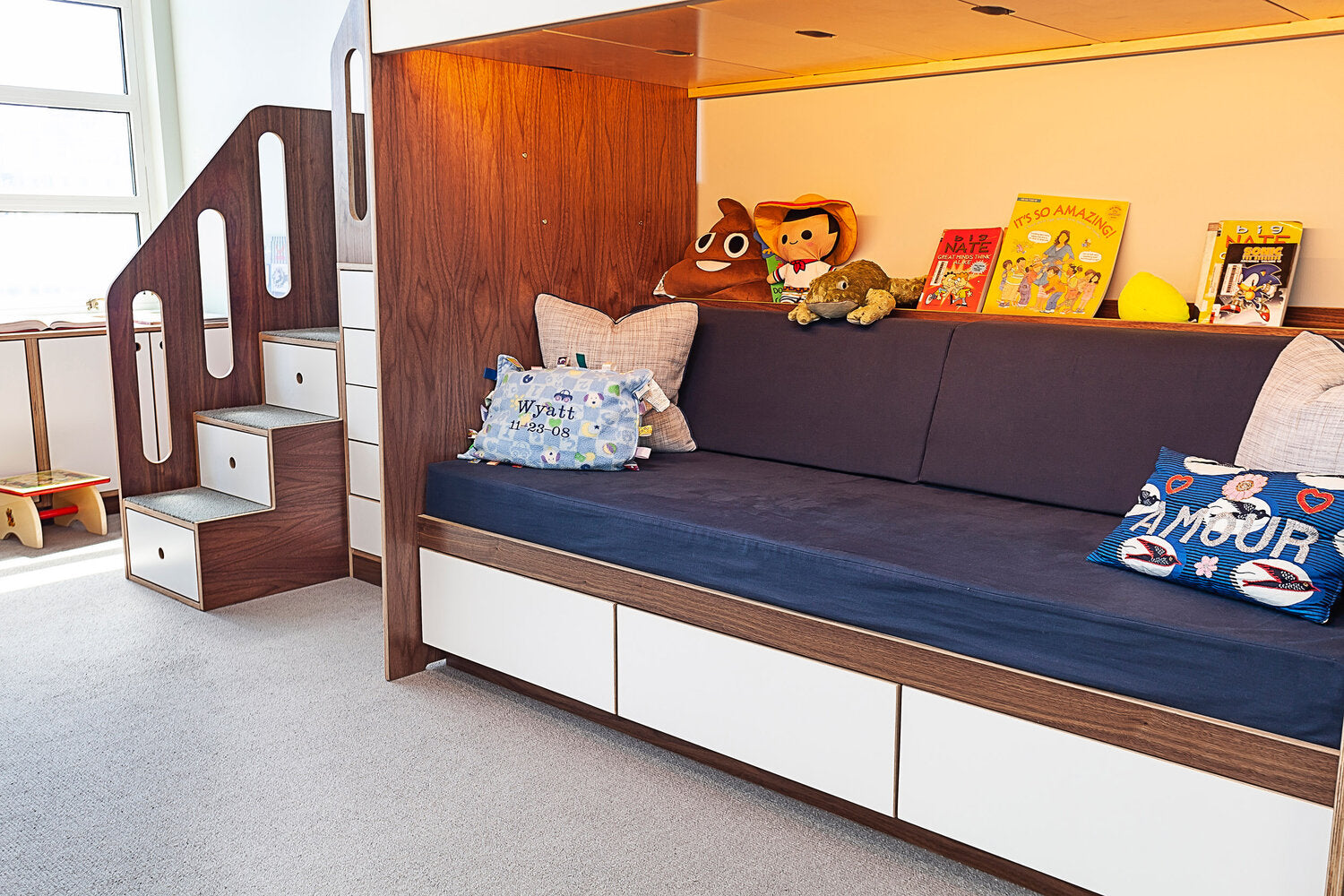 Child’s room with built-in bed, stairs, plush toys, and books for a cozy ambiance.