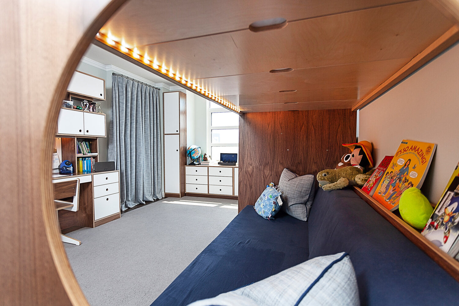 Cozy child’s bedroom with wooden bunk bed, plush toys, and bookshelf.