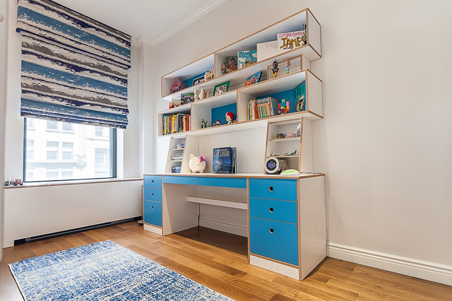 Modern study space with white shelves, blue drawers, and a laptop.