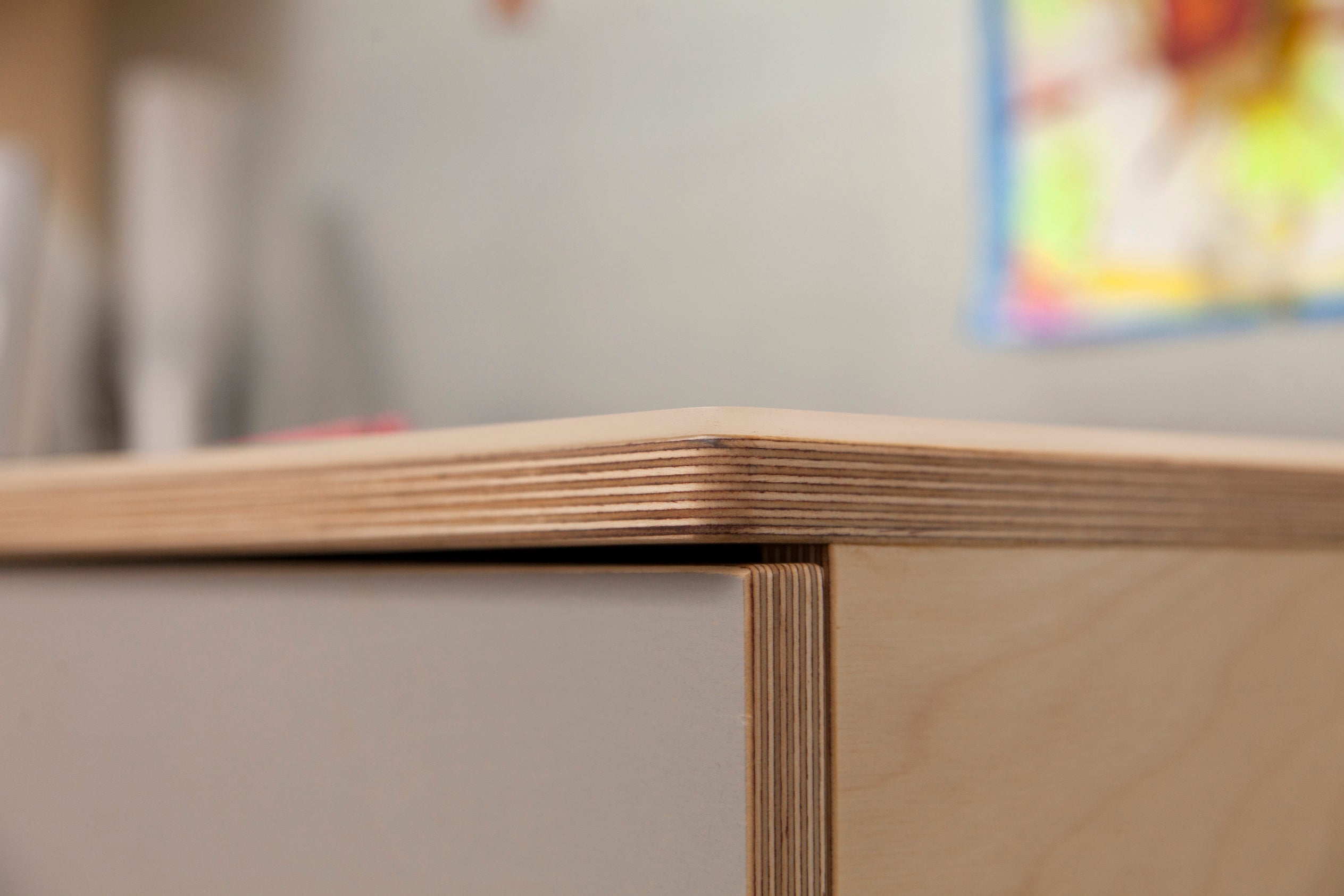 Close-up of a wooden table corner showing precise craftsmanship and layers of material.