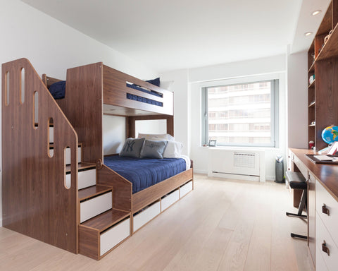 Modern child's room with wooden bunk bed featuring stairs, alongside a desk near a large window.