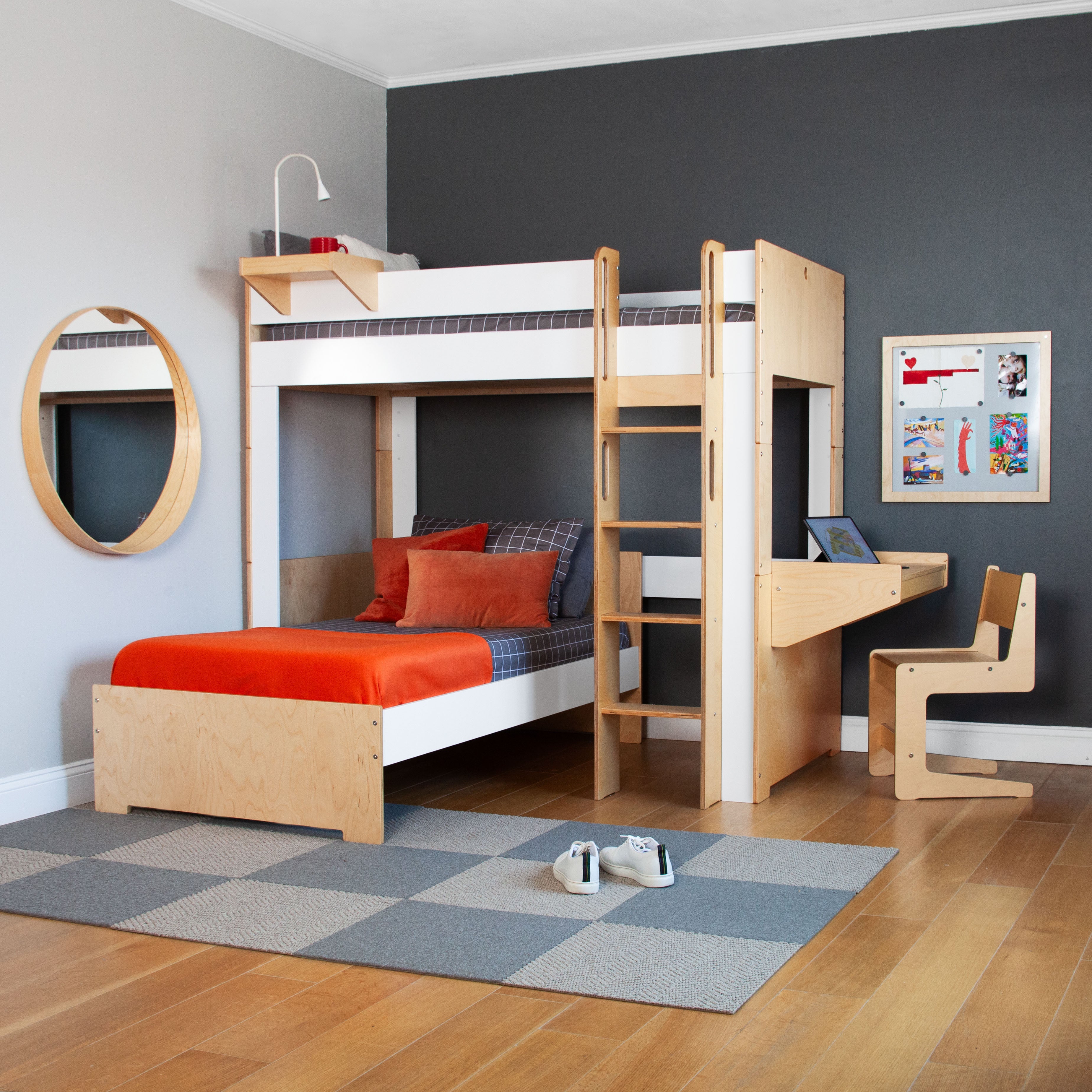 Stylish child's bedroom featuring a bunk bed, sofa bed, study desk, and circular mirror on a gray rug.