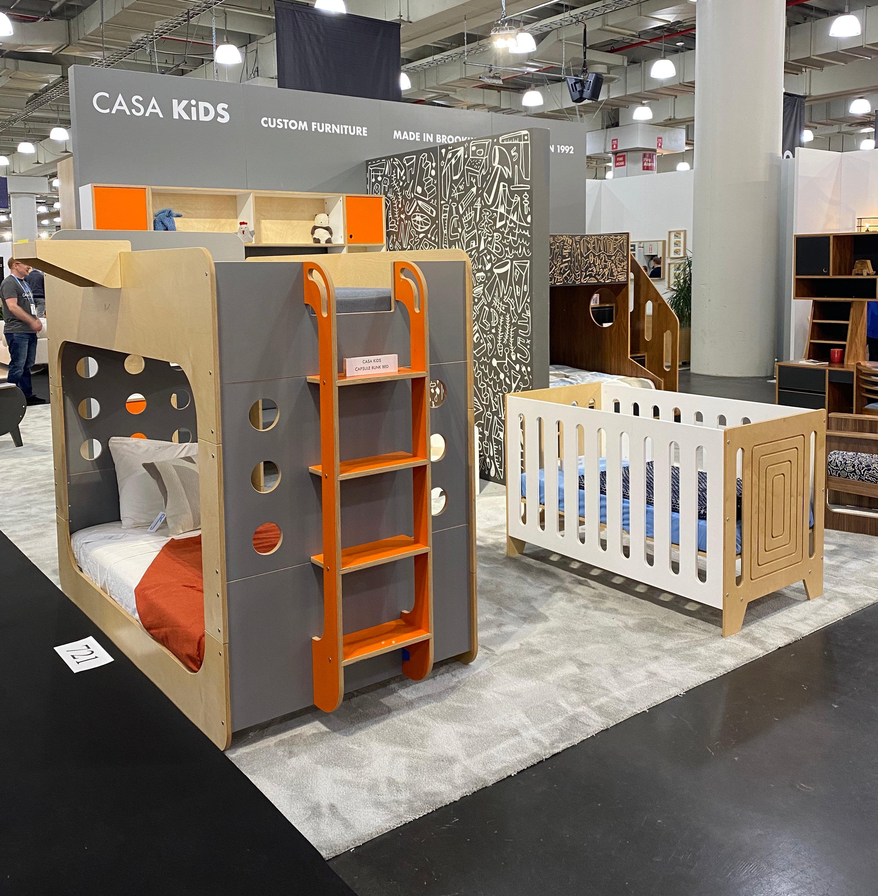 Exhibit of modern children's furniture with a unique bunk bed and a crib at a Casa Kids booth.