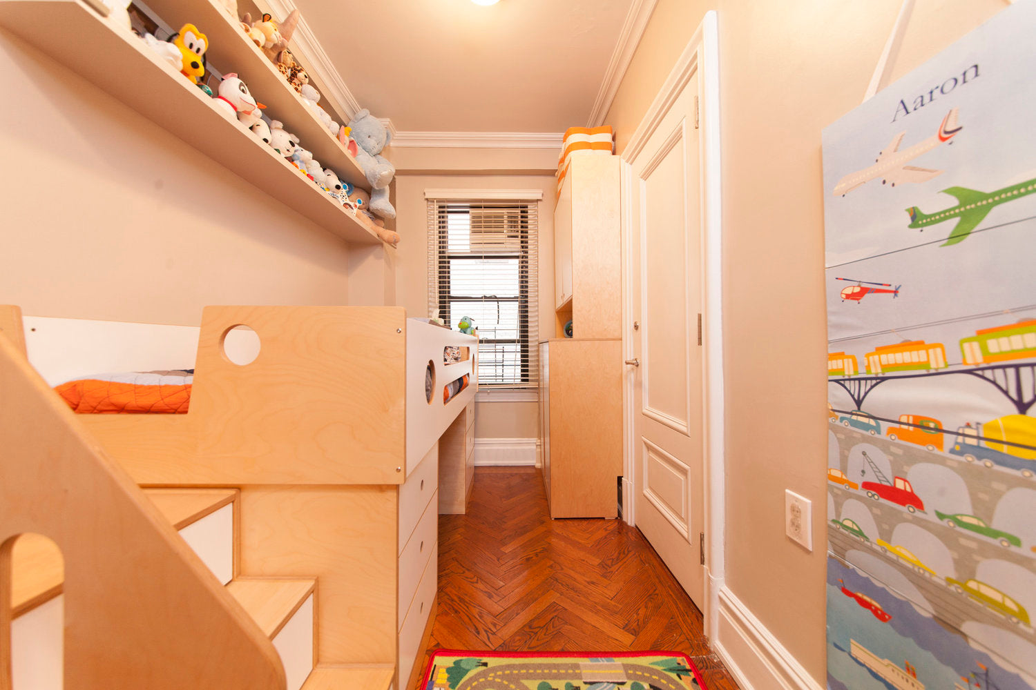 Child’s bedroom with bunk bed, toys, shelves, and colorful rug.