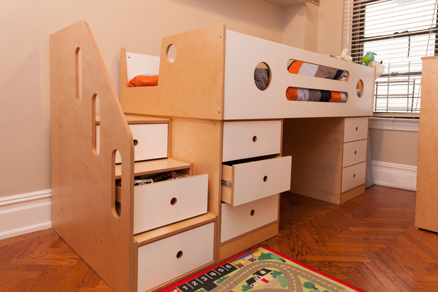 Wooden bunk bed with drawers and a play mat on floor.