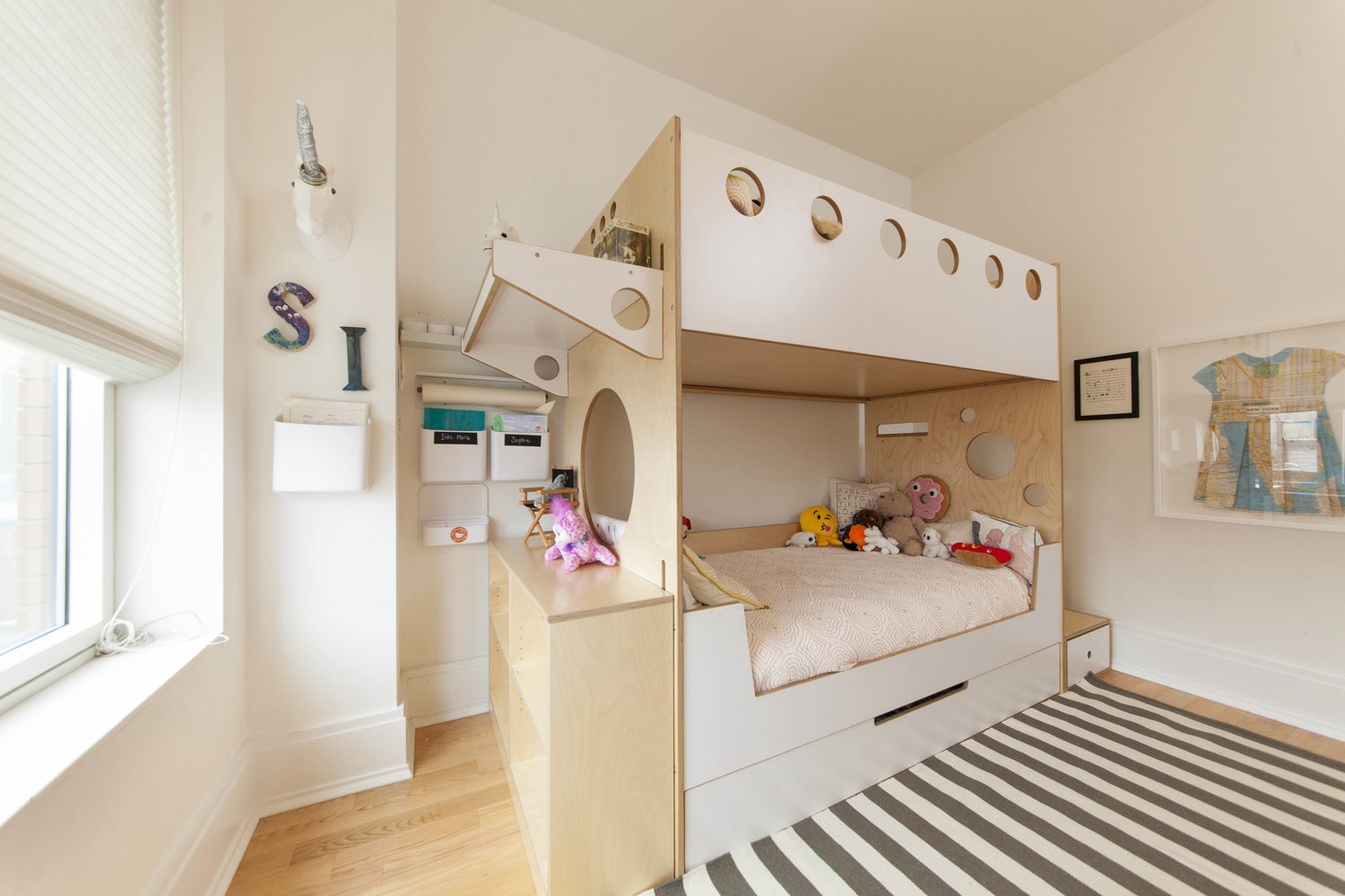 Spacious child's room with a stylish bunk bed, stuffed toys, and a striped rug.