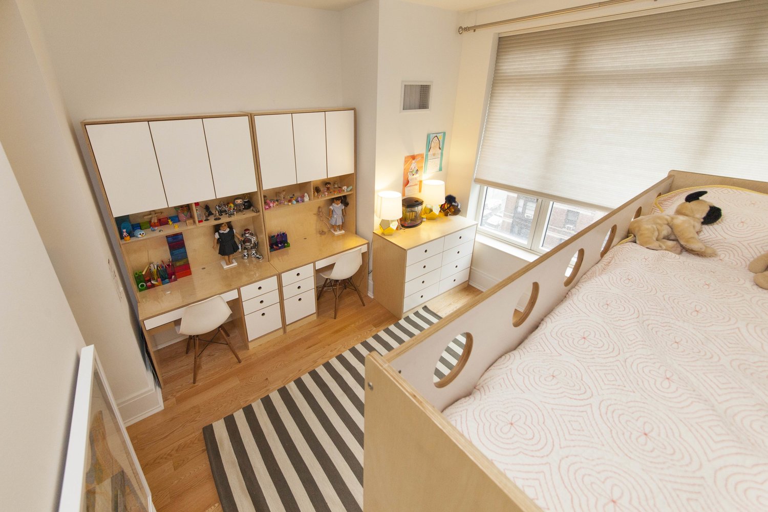 Aerial view of a child's room with a bunk bed, built-in storage, and a striped rug.