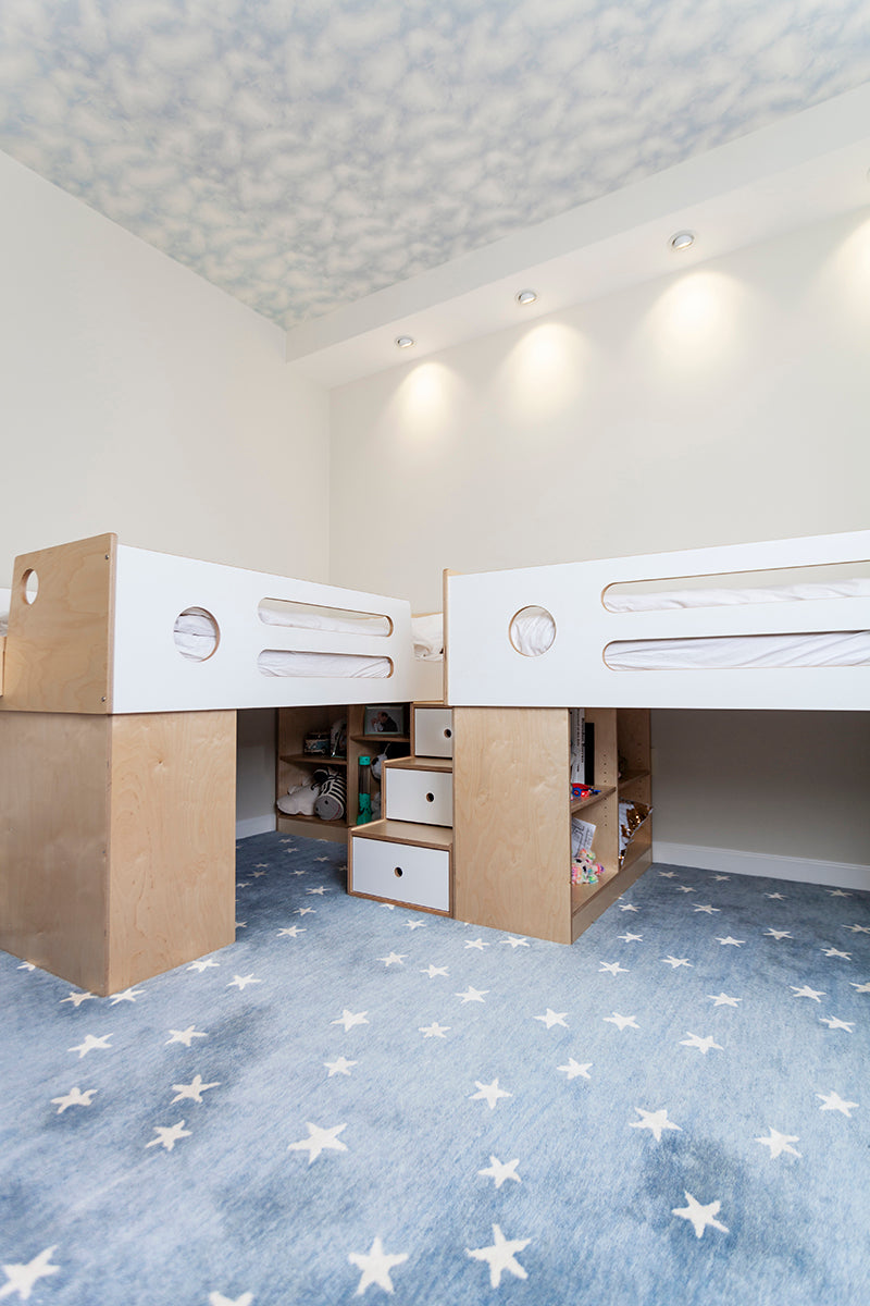 Twin loft beds with storage, starry carpet in child’s room.