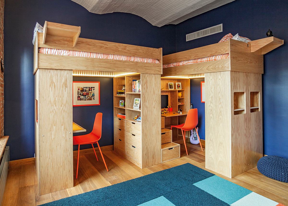 Stylish children's study area with blue walls, integrated desk, and loft bed, featuring warm wood tones.