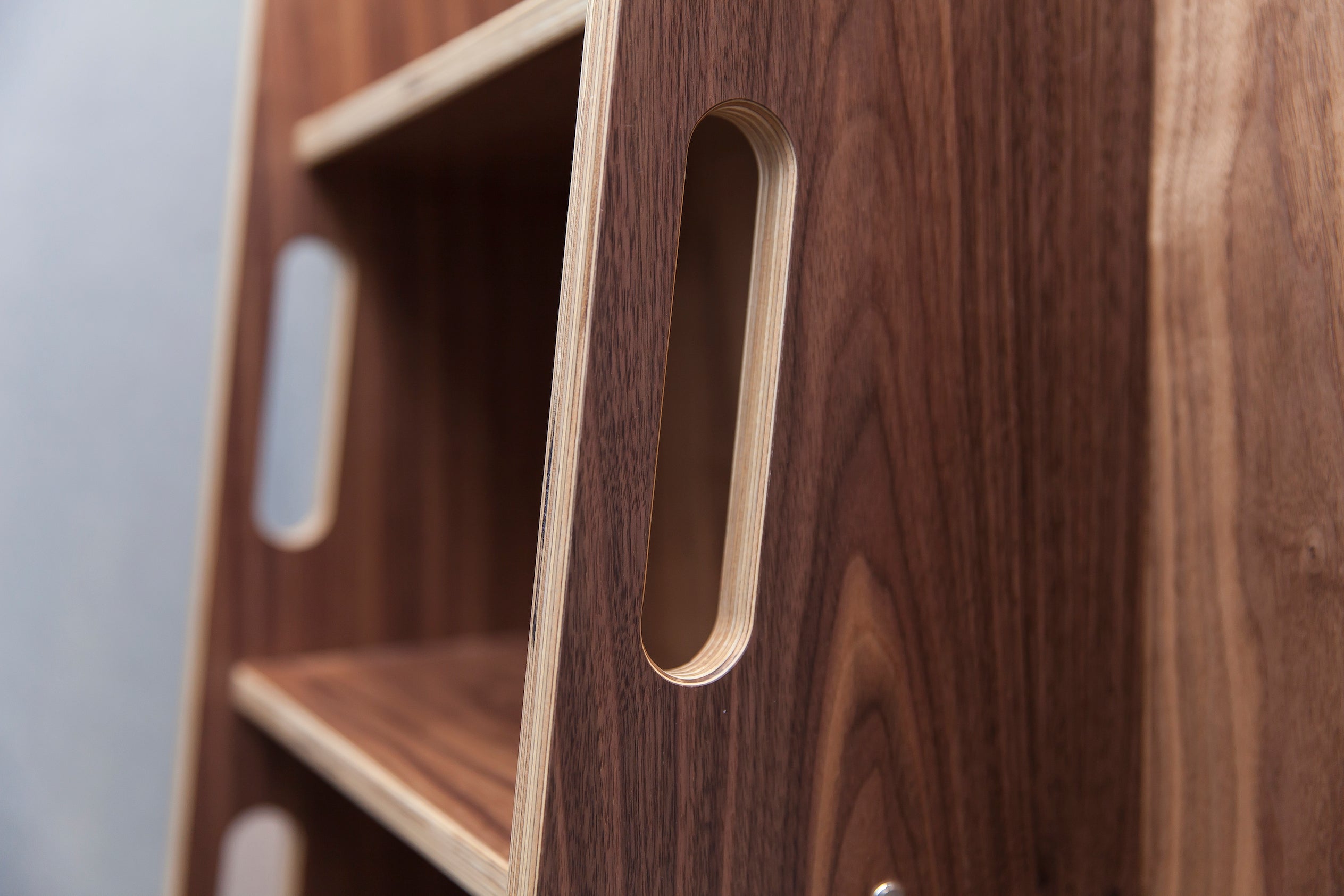Close-up view of a dark wooden bookshelf with oval cutouts as handles, highlighting the design.
