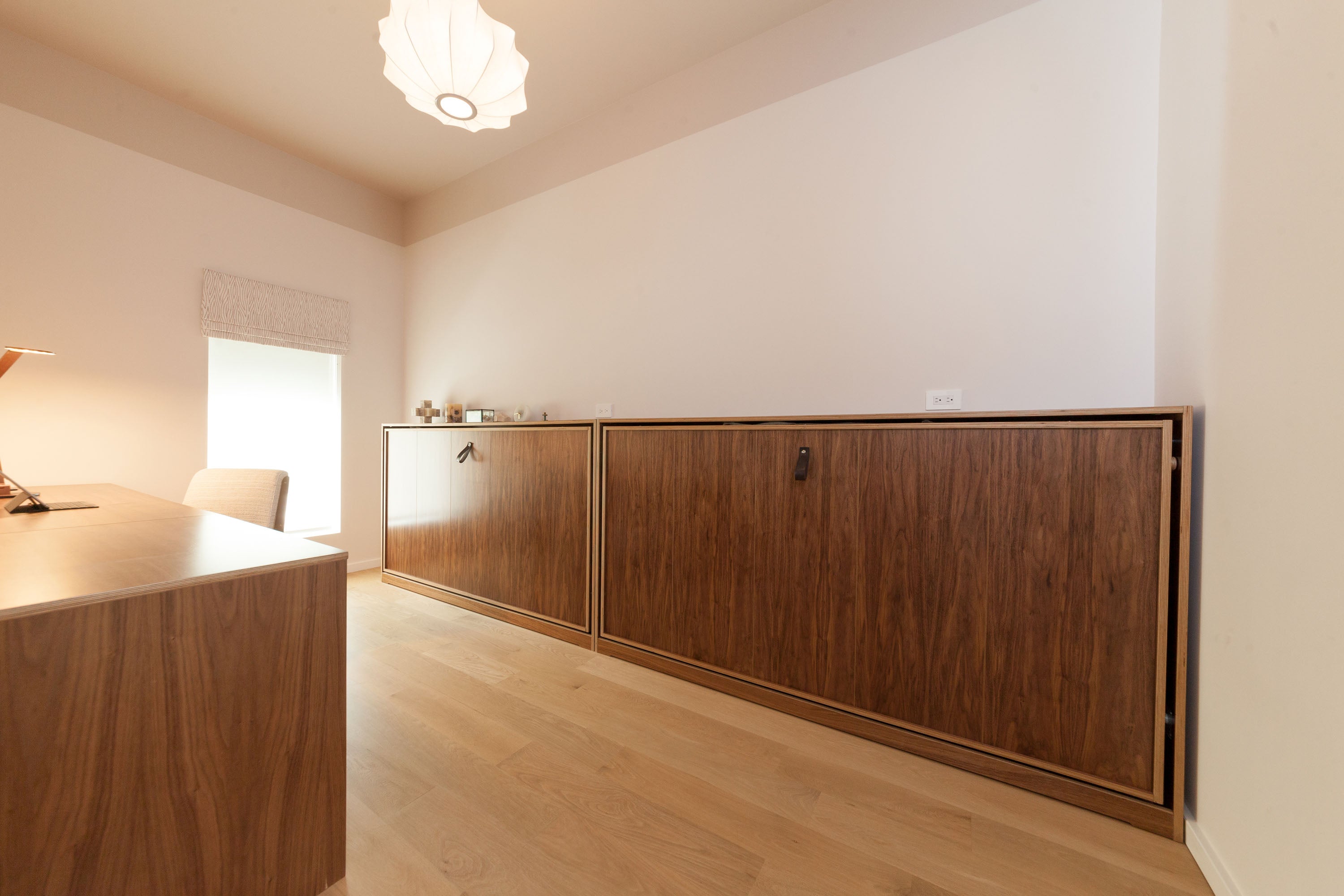 Chic minimalist room with wooden cabinets, white walls, and stylish lamp.