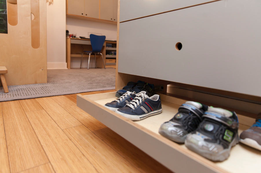 Low-angle view of shoes on a pull-out drawer in a tidy room.