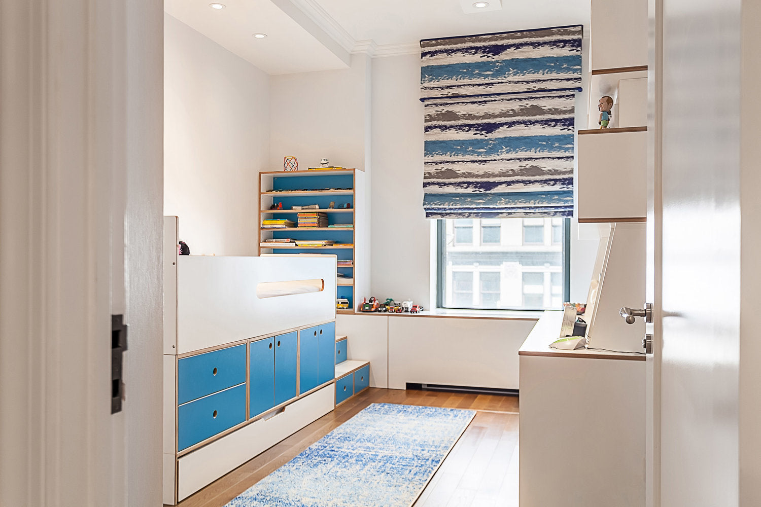 Bright room with blue dresser, bookshelf, artwork, and rug.
