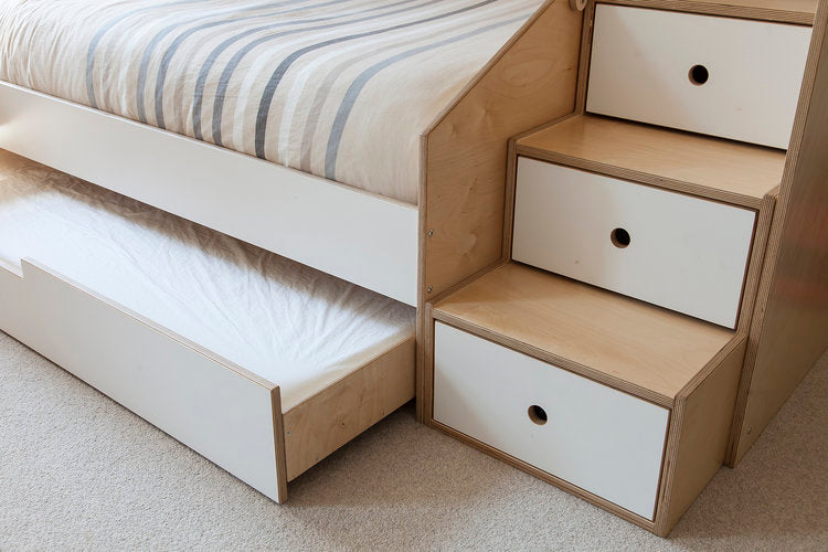 Close-up of a wooden bed with built-in storage drawers and a pull-out trundle bed underneath.