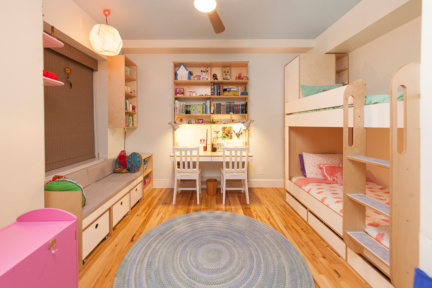 Cozy children’s room with bunk beds, bookshelves, study area, and colorful decor.