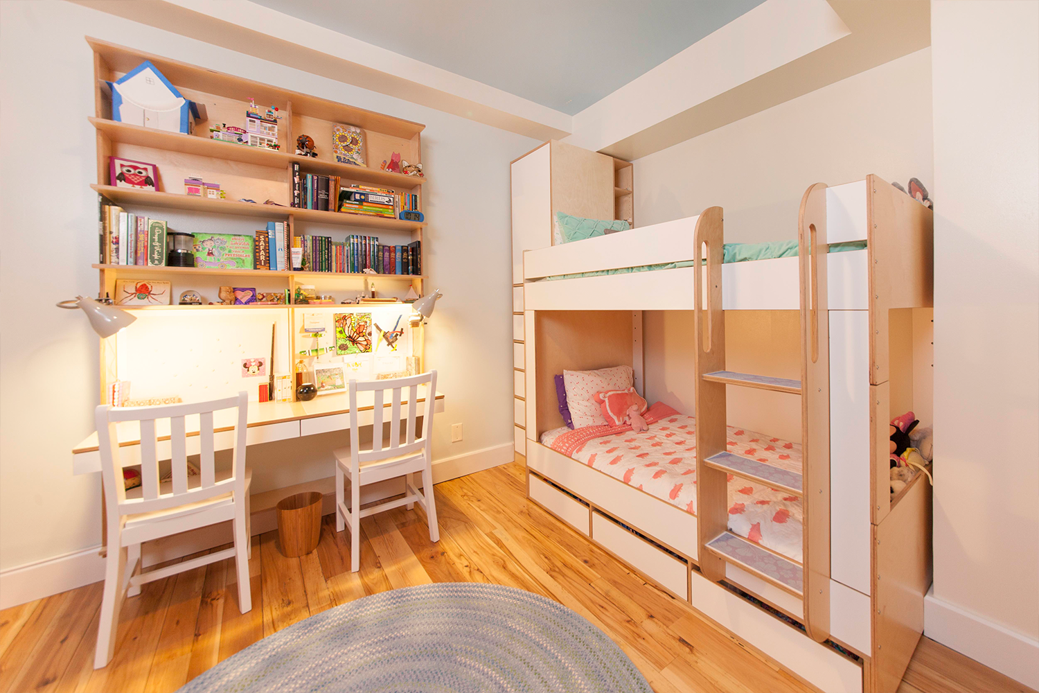 Cozy children’s room with bunk beds, study area, bookshelves, and warm lights.