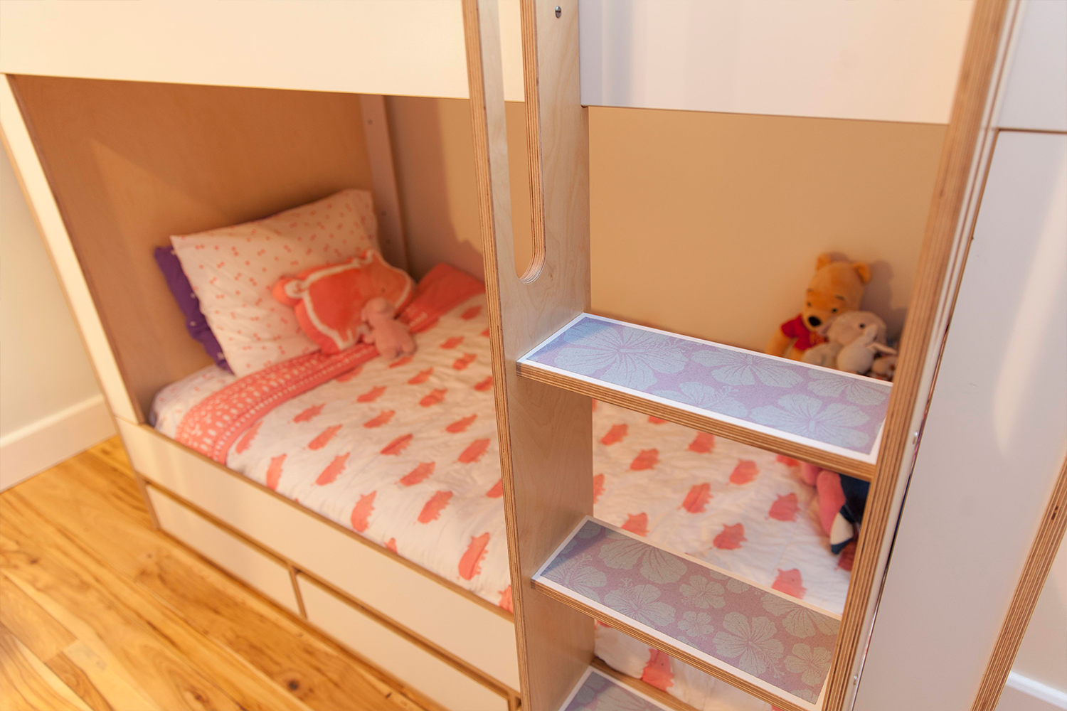 Bunk bed with stairs, plush toys, colorful bedding.