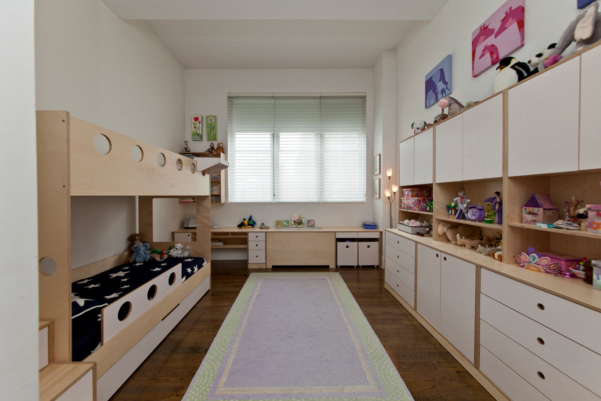 Spacious children's room with bunk beds, extensive storage units, and a neatly arranged play area.